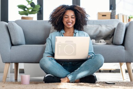 Photo for Shot of happy young woman using her laptop while sitting on the floor at home - Royalty Free Image