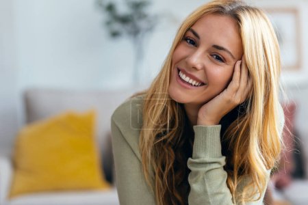 Foto de Retrato de una hermosa mujer joven sonriendo mientras mira la cámara en la sala de estar en casa. - Imagen libre de derechos