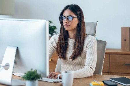 Téléchargez les photos : Plan d'une jeune femme d'affaires travaillant avec un ordinateur dans un bureau moderne. - en image libre de droit