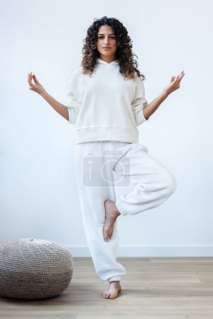 Foto de Tiro de mujer zen pacífica vestida con un chándal blanco haciendo poses de yoga en el estudio - Imagen libre de derechos