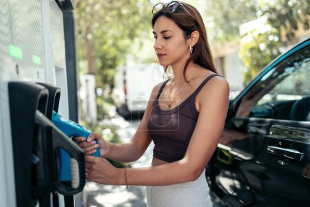 Photo for Shot of young woman charging electro car at the electric gas station - Royalty Free Image