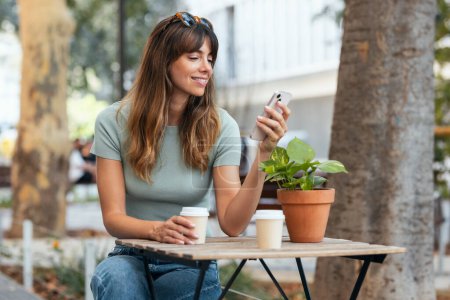 Téléchargez les photos : Prise de vue de belle jeune femme d'affaires textos avec son téléphone portable dans la terrasse du café. - en image libre de droit