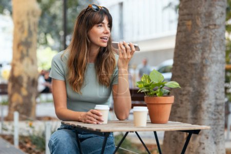 Téléchargez les photos : Prise de vue de belle jeune femme d'affaires textos avec son téléphone portable dans la terrasse du café. - en image libre de droit