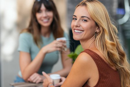 Photo for Shot of two attractive friends enjoying coffee together while talking and laughing sitting on the terrace of a bar. - Royalty Free Image