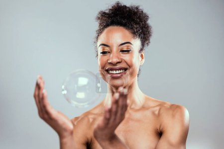 Téléchargez les photos : Prise de vue d'une jolie femme mature jouant avec du savon et des bulles d'eau sur un blanc isolé - en image libre de droit