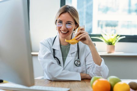 Photo for Shot of beautiful young woman nutritionist playing with a banana as if it were a telephone on a nutritionist consultation - Royalty Free Image