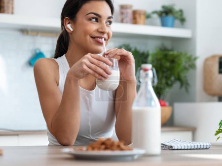 Aufnahme einer schönen Frau, die morgens in der Küche steht und ein Glas Milch trinkt