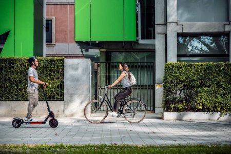Un disparo de mujer alegre en bicicleta cruza a un hombre concentrado en un scooter eléctrico por la ciudad