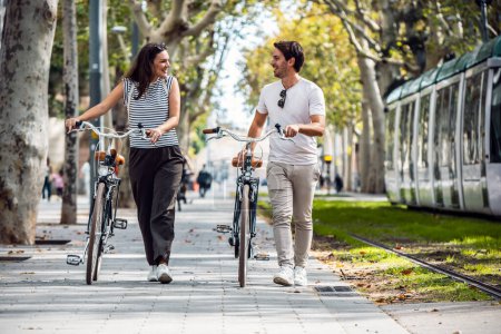 Photo for Shot of happy loving couple cycling while looking each other in the city - Royalty Free Image