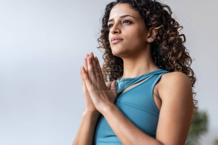 Téléchargez les photos : Tourné de zen paisible femme vêtue d'un survêtement faisant des poses de yoga dans le salon à la maison - en image libre de droit
