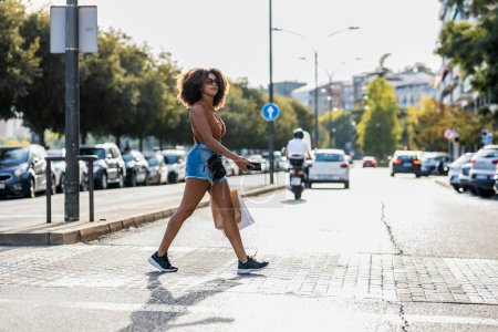 Shot of beautiful woman using smartphone while crossing a zebra crossing in the city