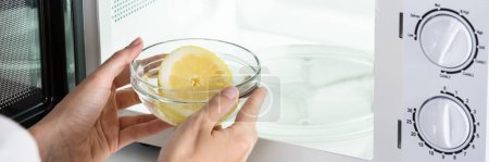 Foto de Horno de microondas de limpieza de mujer con fruta de limón - Imagen libre de derechos