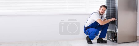Photo for Fridge Appliance Repair At Home. Man Fixing Refrigerator - Royalty Free Image
