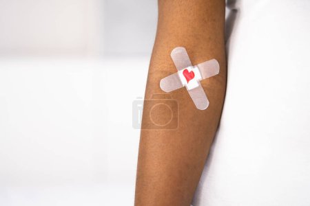 Téléchargez les photos : Concept de don de sang. African American Donor avec pansement et coeur - en image libre de droit