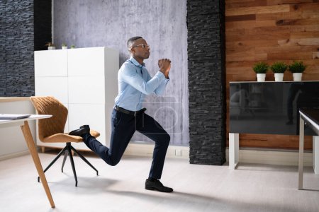 Téléchargez les photos : Un employé africain fait un exercice de squat éclaté bulgare au bureau - en image libre de droit
