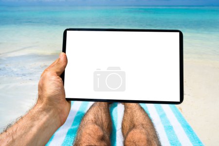 Téléchargez les photos : Homme utilisant la tablette tout en se relaxant sur la chaise de plage - en image libre de droit