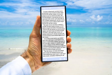 Photo for Woman Reading E-book On Tablet At Beach - Royalty Free Image