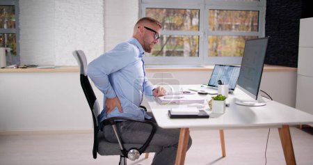 Foto de Dolor de espalda Mala postura Hombre sentado en la oficina - Imagen libre de derechos