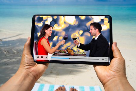 Foto de Mujer viendo la película de televisión o vídeo en la tableta en la playa - Imagen libre de derechos