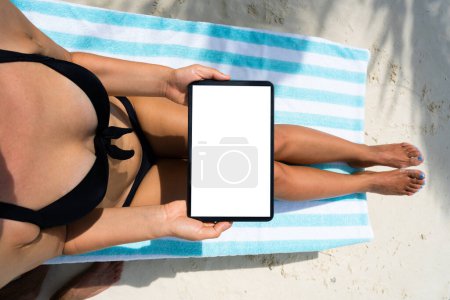 Foto de Mujer usando la tableta mientras se relaja en la silla de playa - Imagen libre de derechos