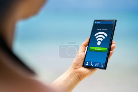 Photo for Person Hand With Internet On Mobile Phone At The Beach - Royalty Free Image