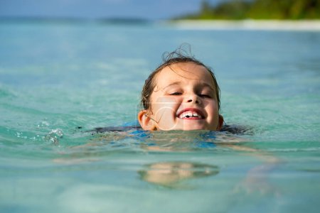 Téléchargez les photos : Happy Kid Apprendre à nager avec un disque de natation ou anneau dans l'eau. Enfant sur la plage - en image libre de droit