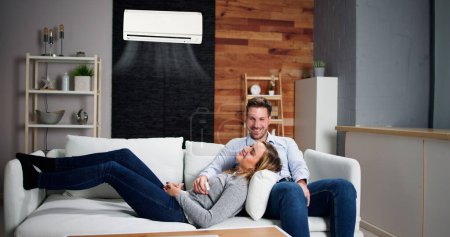 Téléchargez les photos : Couple familial heureux utilisant le climatiseur. Appartement AC - en image libre de droit