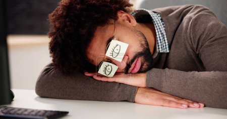 Foto de Cansado hombre afroamericano durmiendo en el escritorio - Imagen libre de derechos