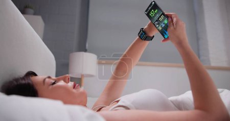 Foto de Woman's Hand Showing Heart Rate On Smart Watch And Cell Phone - Imagen libre de derechos