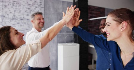 Téléchargez les photos : Happy Businesspeople Giving High Five Over Desk At Workplace - en image libre de droit