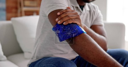 Foto de Hombre usando paquete de gel de hielo en brazo lesionado - Imagen libre de derechos