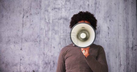 Téléchargez les photos : Homme faisant l'annonce en utilisant mégaphone contre fond gris - en image libre de droit