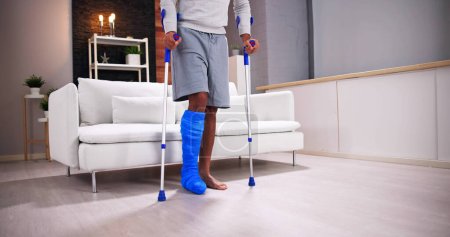 Photo for Young Man Using Crutches To Walking At Home - Royalty Free Image