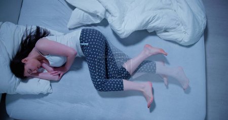 Téléchargez les photos : Woman With RLS - Restless Legs Syndrome. Sleeping In Bed - en image libre de droit