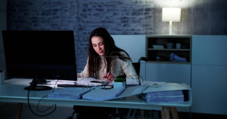 Photo for Accountant Woman In Office At Night With Tax Documents - Royalty Free Image