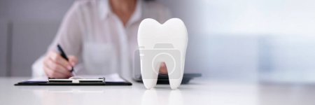 Photo for Dentist Paperwork At Desk In Front Of Teeth - Royalty Free Image