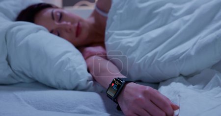 Foto de Monitor de frecuencia cardíaca de seguimiento del sueño portátil Smartwatch en la cama - Imagen libre de derechos