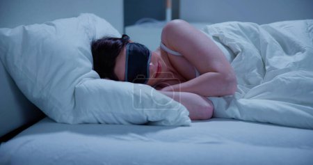Téléchargez les photos : Gros plan de belle jeune femme dormant sur le lit avec masque pour les yeux - en image libre de droit