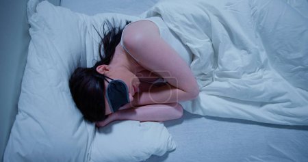 Téléchargez les photos : Gros plan de belle jeune femme dormant sur le lit avec masque pour les yeux - en image libre de droit