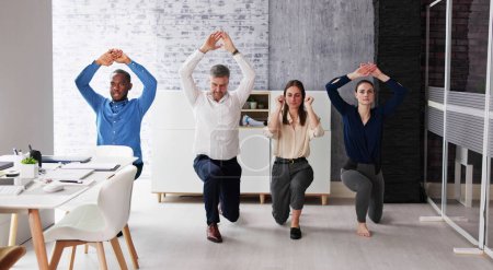 Foto de Happy Young Businesspeople Doing Stretching Exercise In Office - Imagen libre de derechos