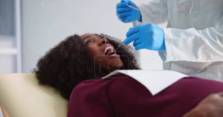 Foto de Dentista Tratando los Dientes De Mujer Embarazada Joven Paciente Mintiendo En Clínica - Imagen libre de derechos