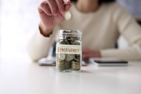 Foto de Woman Saving Money In Emergency Jar Budget - Imagen libre de derechos
