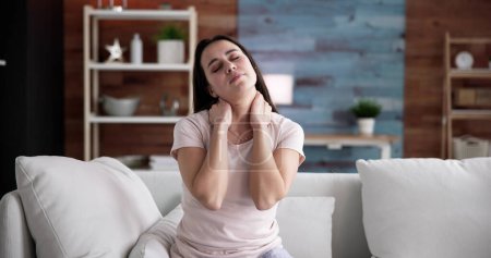 Photo for Young Woman Suffering From Neck Pain At Home - Royalty Free Image