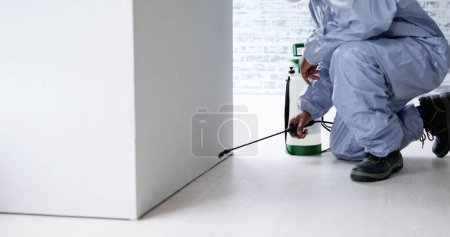 Photo for Pest Control Exterminator Man Spraying Termite Pesticide In Office - Royalty Free Image