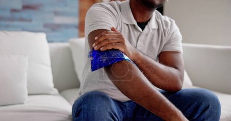 Foto de Hombre usando paquete de gel de hielo en brazo lesionado - Imagen libre de derechos