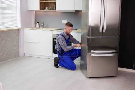 Foto de Hombre trabajador reparación de refrigerador con destornillador en casa - Imagen libre de derechos