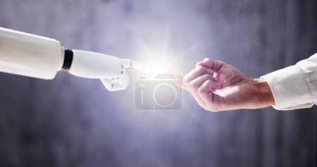 Téléchargez les photos : Robot toucher doigt humain sur fond gris - en image libre de droit