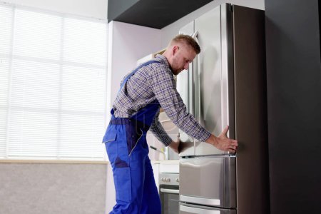 Foto de Hombre trabajador reparación de refrigerador con destornillador en casa - Imagen libre de derechos
