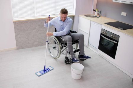 Photo for Person With Disabilty Cleaning Kitchen Floor Using Mop - Royalty Free Image