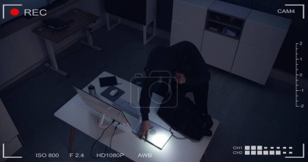 Téléchargez les photos : Thief Stealing Computer From Office At Night - en image libre de droit
